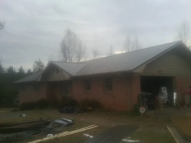 Gray metal roof on a stucco house with an attached garage in Stewart