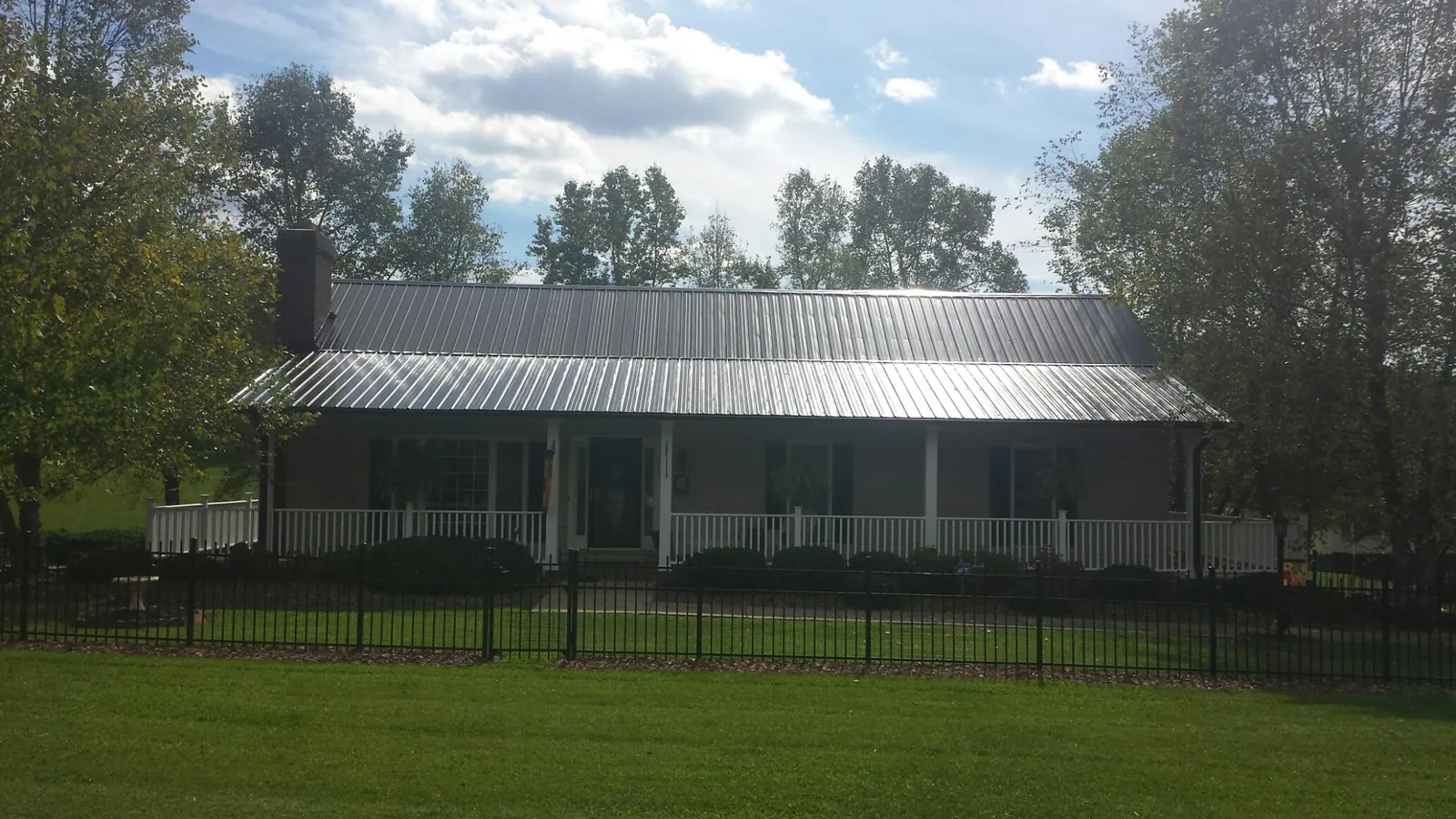Gray metal roof on a brick ranch with a full width front porch — Gutter Guard Installation work by our crew in Stewart